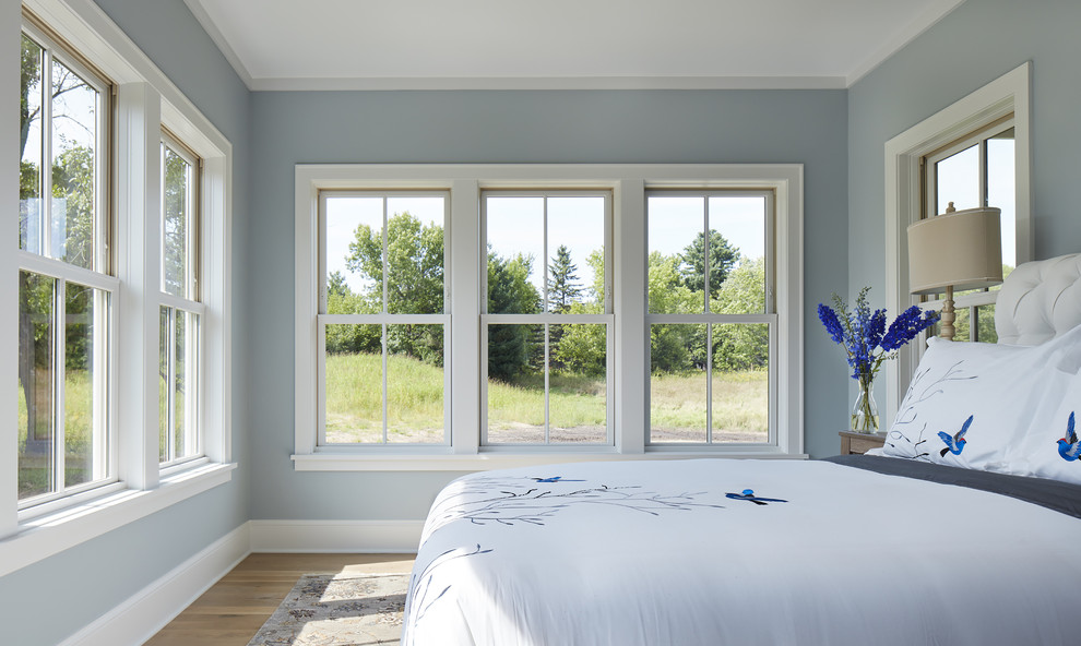 Mittelgroßes Landhausstil Hauptschlafzimmer mit blauer Wandfarbe und hellem Holzboden in Minneapolis
