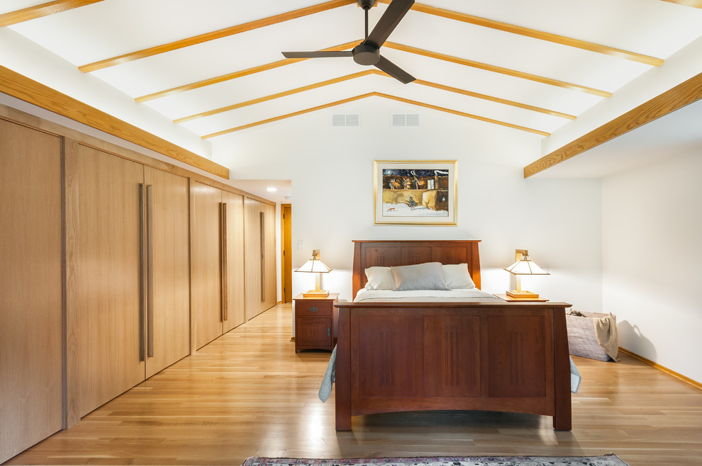 Modelo de dormitorio principal vintage de tamaño medio con paredes blancas, suelo de madera clara y suelo beige