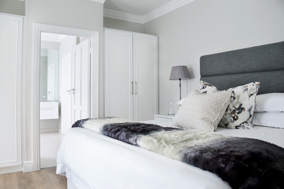 Ejemplo de habitación de invitados contemporánea de tamaño medio con paredes blancas y suelo laminado