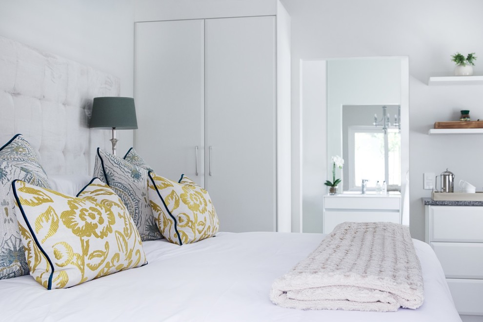 Modelo de habitación de invitados contemporánea de tamaño medio con paredes blancas y suelo laminado