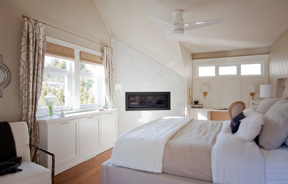 Diseño de dormitorio clásico renovado con paredes beige, suelo de madera en tonos medios, chimenea lineal y marco de chimenea de piedra