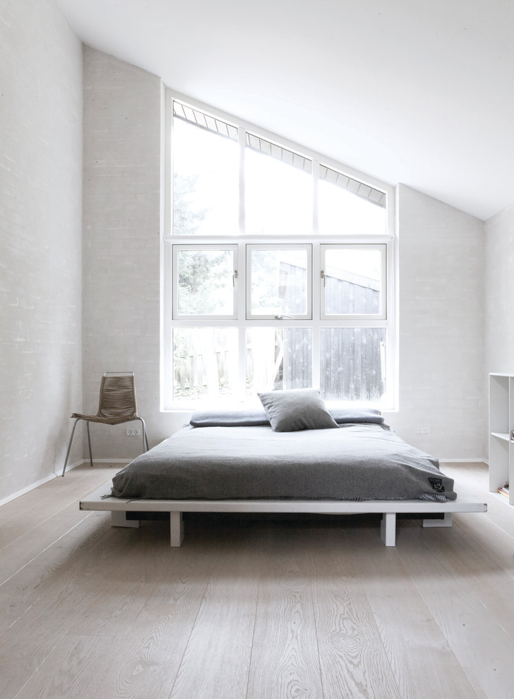 На фото: большая хозяйская спальня в скандинавском стиле с белыми стенами и деревянным полом с