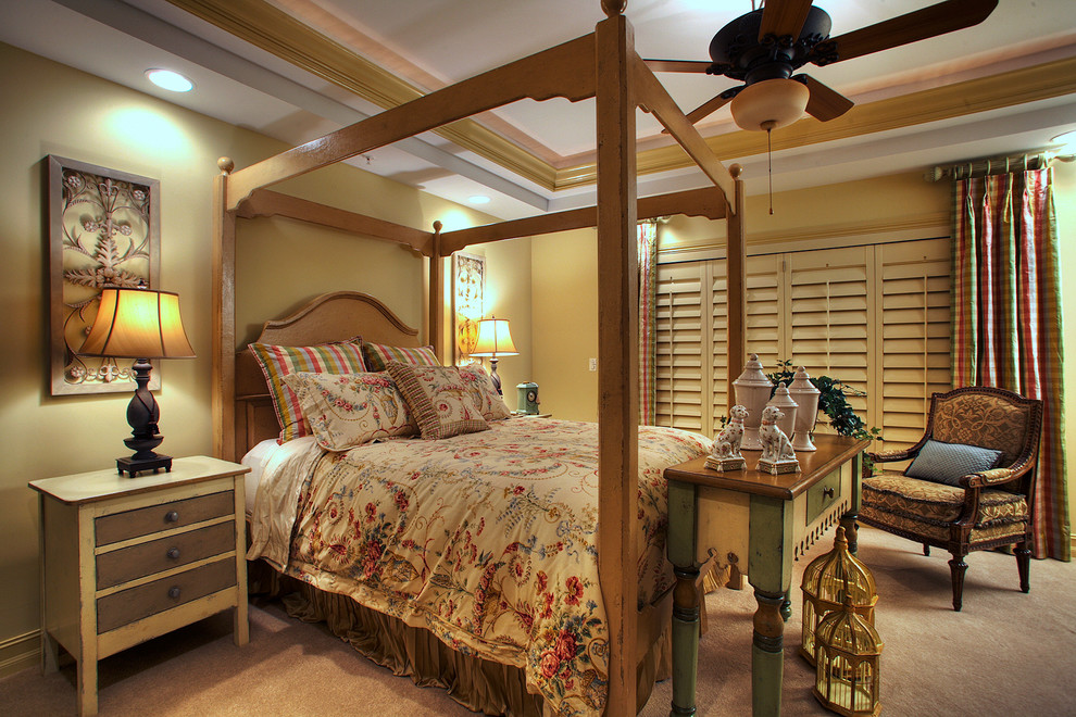 На фото: большая хозяйская спальня с желтыми стенами, ковровым покрытием, стандартным камином и фасадом камина из дерева