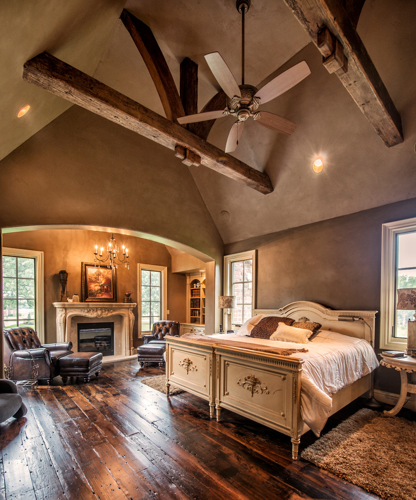 Großes Hauptschlafzimmer mit brauner Wandfarbe, dunklem Holzboden, Kamin, verputzter Kaminumrandung und braunem Boden in Sonstige