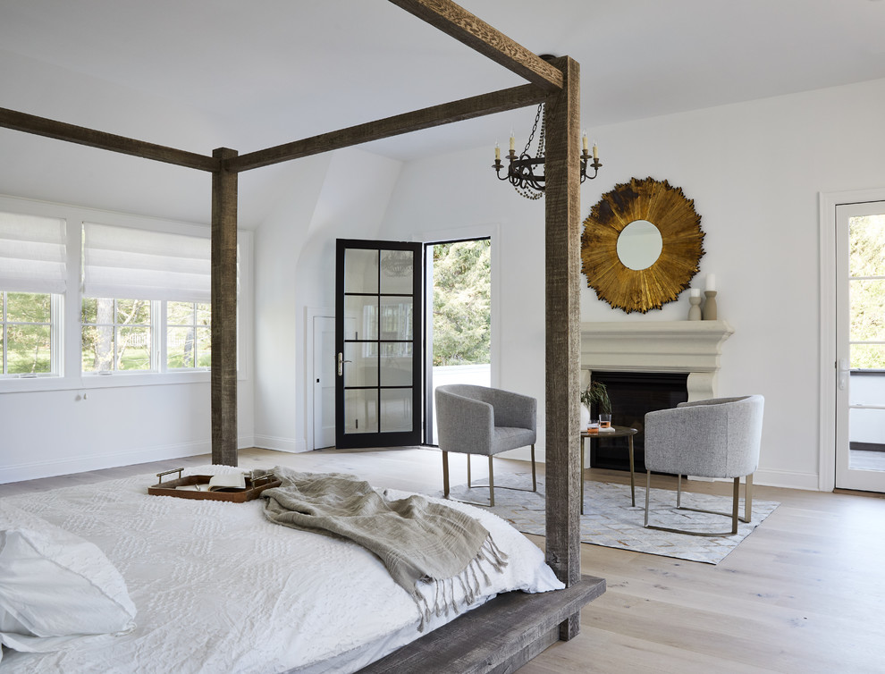 Bild på ett lantligt sovrum, med vita väggar, ljust trägolv, en standard öppen spis och beiget golv