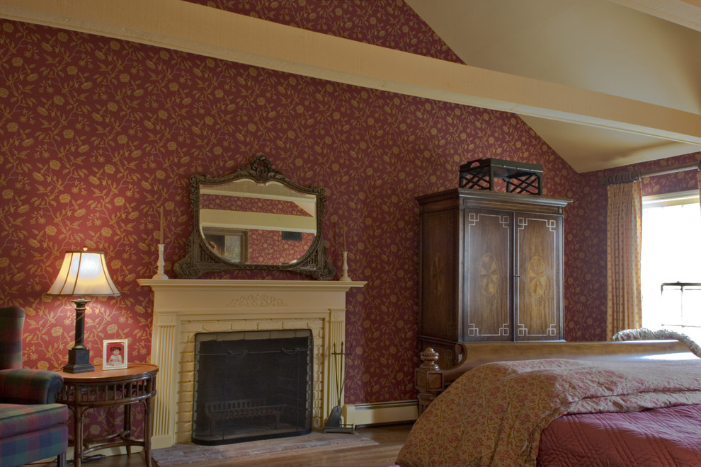 На фото: большая хозяйская спальня в классическом стиле с красными стенами, паркетным полом среднего тона, стандартным камином и фасадом камина из кирпича