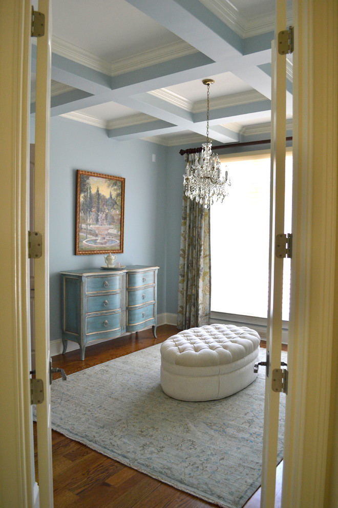Imagen de dormitorio principal tradicional de tamaño medio sin chimenea con paredes azules, suelo de madera clara y suelo marrón