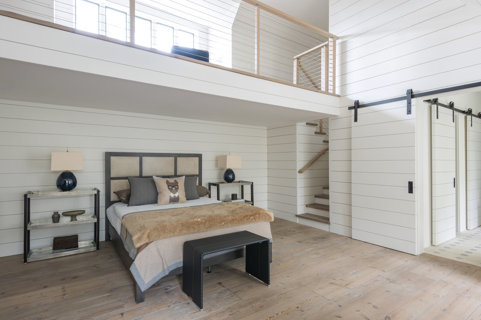 Diseño de dormitorio tipo loft de estilo de casa de campo grande con paredes blancas y marco de chimenea de piedra
