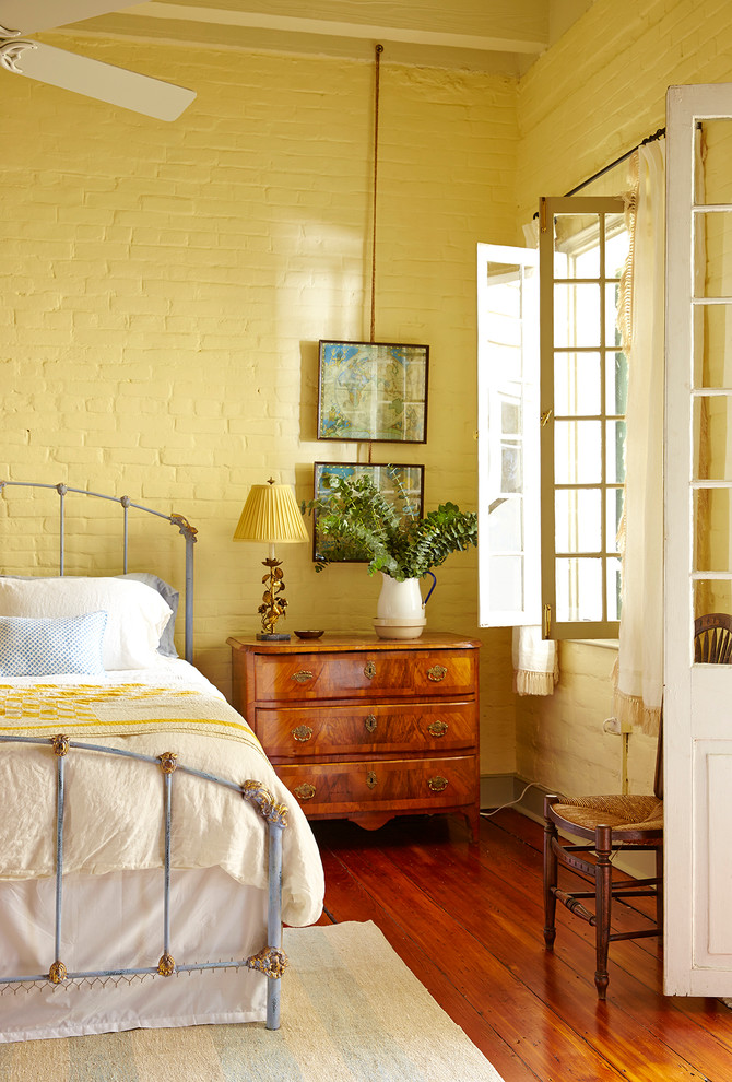 Idée de décoration pour une chambre grise et jaune style shabby chic avec un mur jaune et parquet foncé.