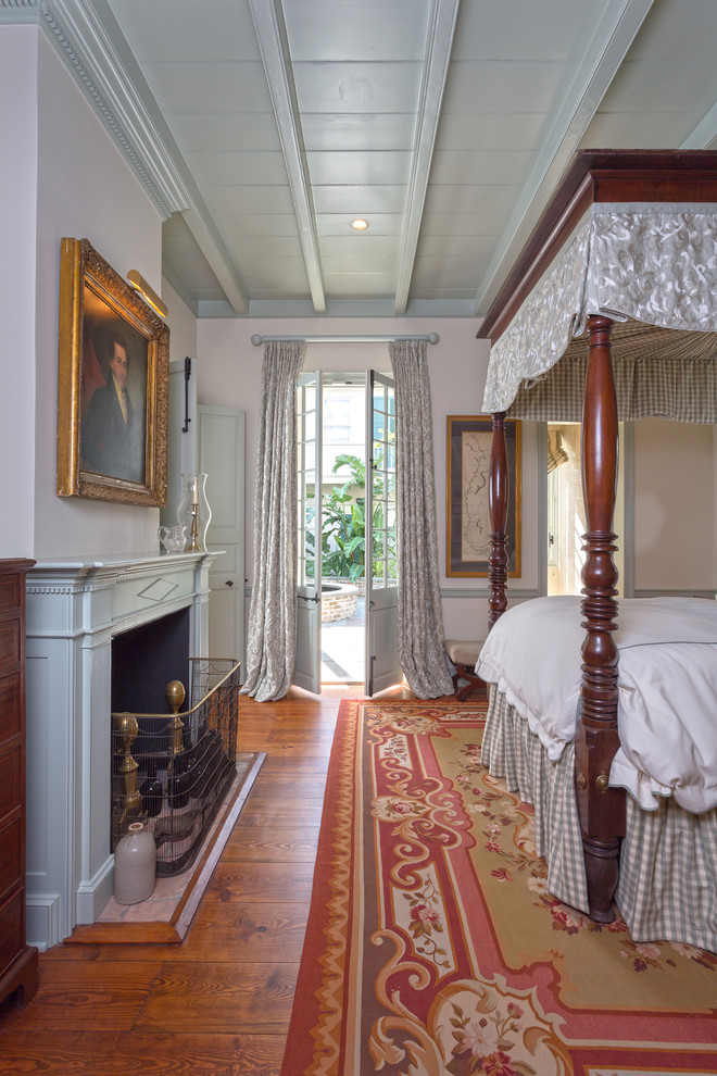 Design ideas for a traditional grey and pink bedroom in New Orleans with a standard fireplace, orange floors and a dado rail.