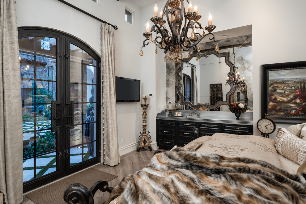 Ejemplo de habitación de invitados romántica extra grande con paredes blancas, suelo de madera oscura, chimenea de doble cara, marco de chimenea de piedra y suelo marrón