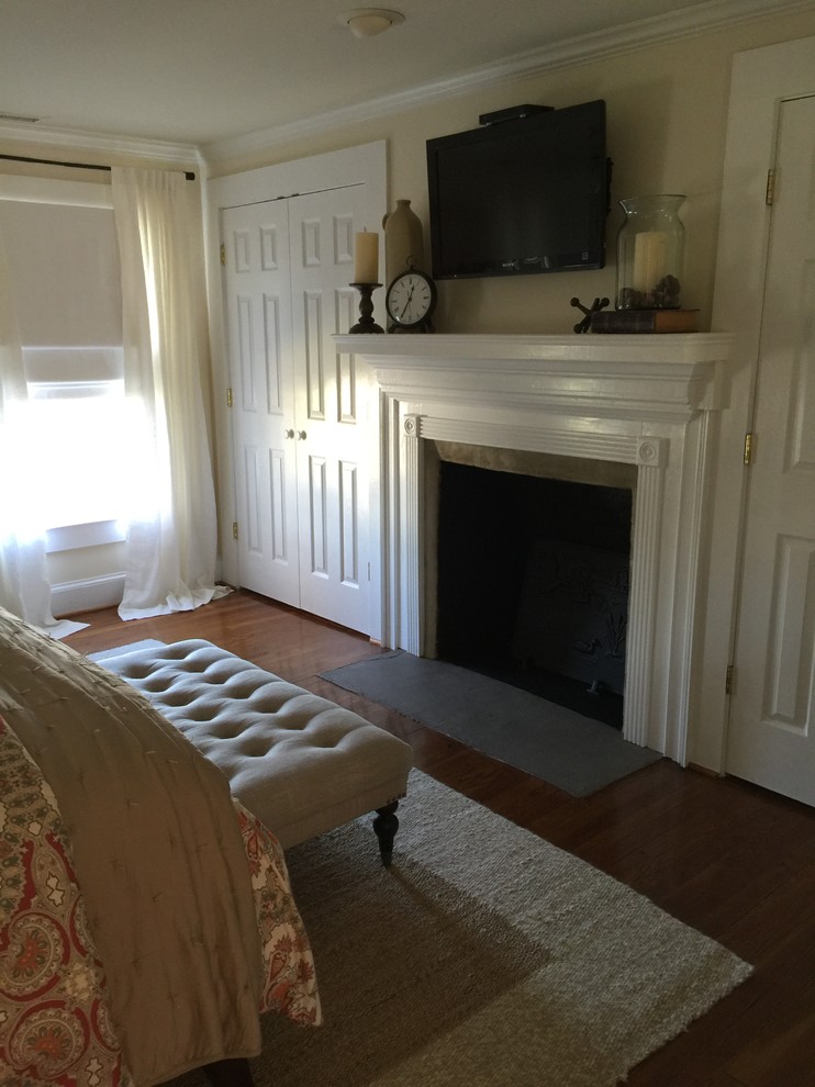 Example of a mid-sized farmhouse master medium tone wood floor bedroom design in Raleigh with white walls, a standard fireplace and a plaster fireplace