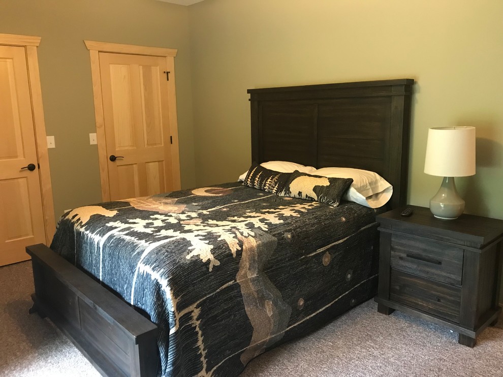 This is an example of a rustic guest bedroom in Milwaukee with green walls, carpet and brown floors.