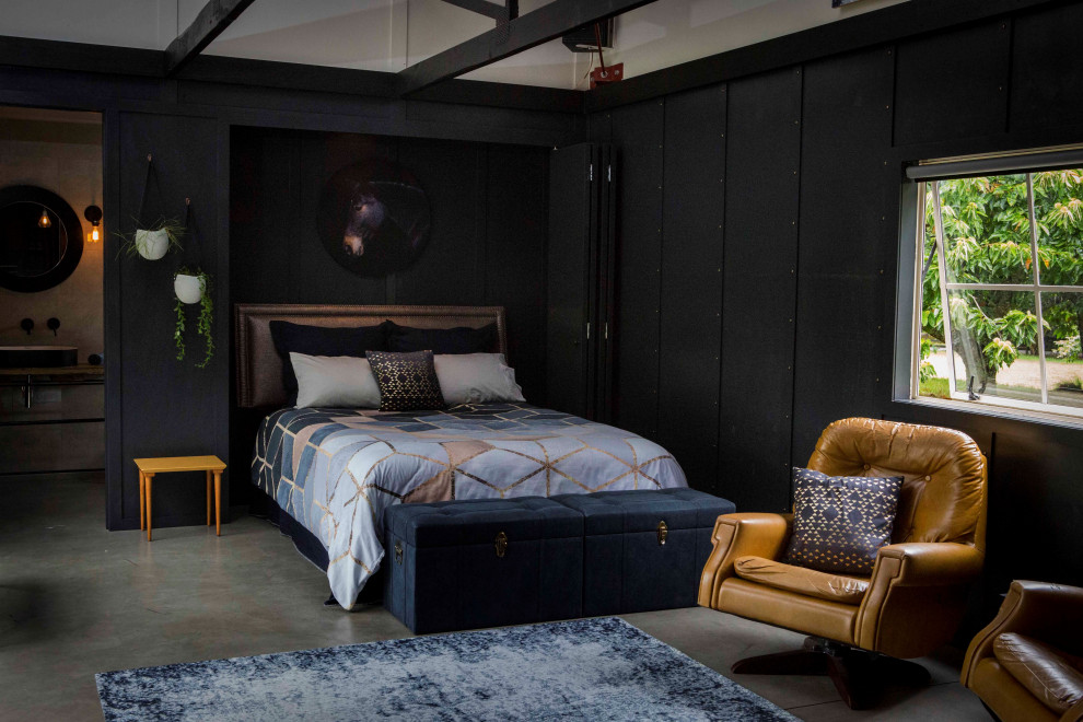 На фото: большая гостевая спальня (комната для гостей) в стиле лофт с черными стенами, бетонным полом, серым полом, сводчатым потолком и панелями на стенах с