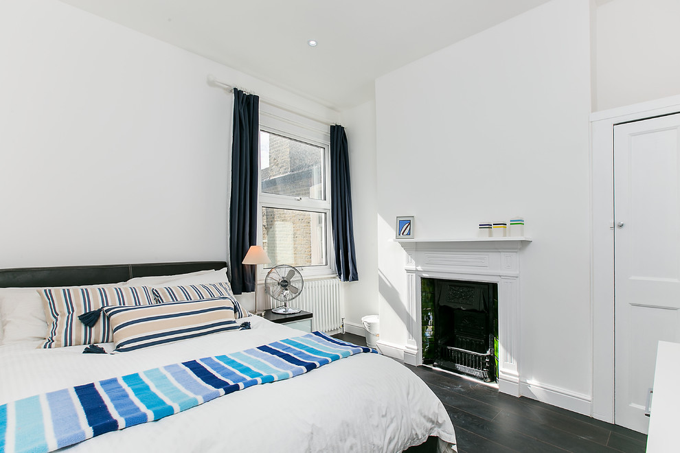 ロンドンにある中くらいなトランジショナルスタイルのおしゃれな客用寝室 (白い壁、濃色無垢フローリング、標準型暖炉、木材の暖炉まわり) のレイアウト