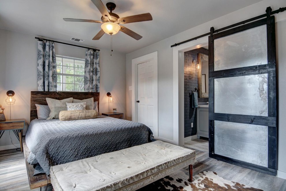 Diseño de dormitorio principal de estilo de casa de campo grande sin chimenea con paredes grises, suelo de madera en tonos medios y suelo gris