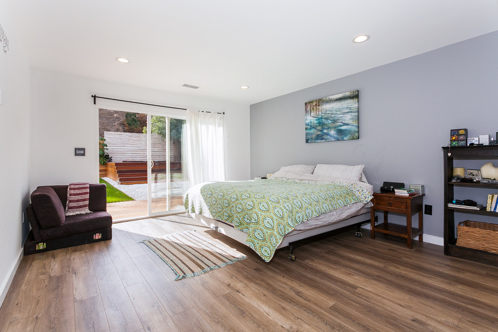 ロサンゼルスにある広いコンテンポラリースタイルのおしゃれな主寝室 (白い壁、無垢フローリング、暖炉なし、コンクリートの暖炉まわり、茶色い床)