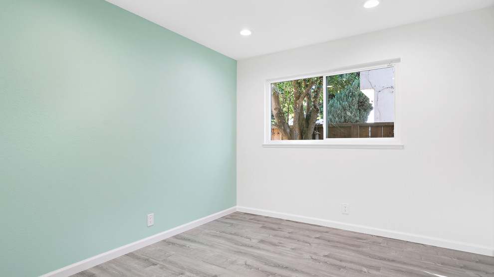 サンフランシスコにある中くらいなトランジショナルスタイルのおしゃれな客用寝室 (青い壁、ラミネートの床、暖炉なし、茶色い床)