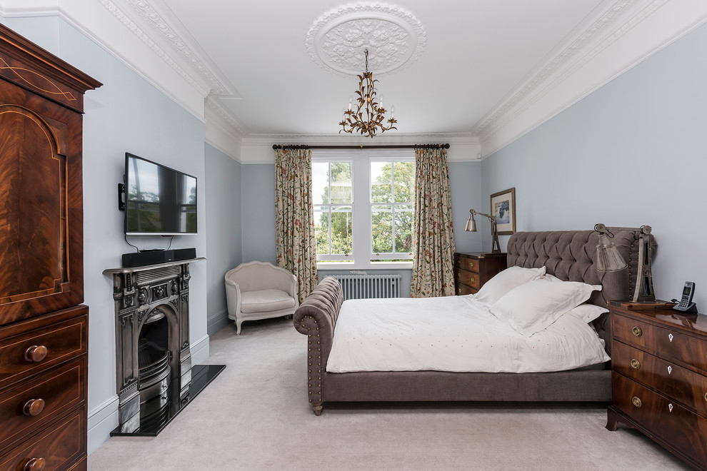 Foto de dormitorio principal clásico renovado grande con paredes azules, moqueta, todas las chimeneas y marco de chimenea de metal