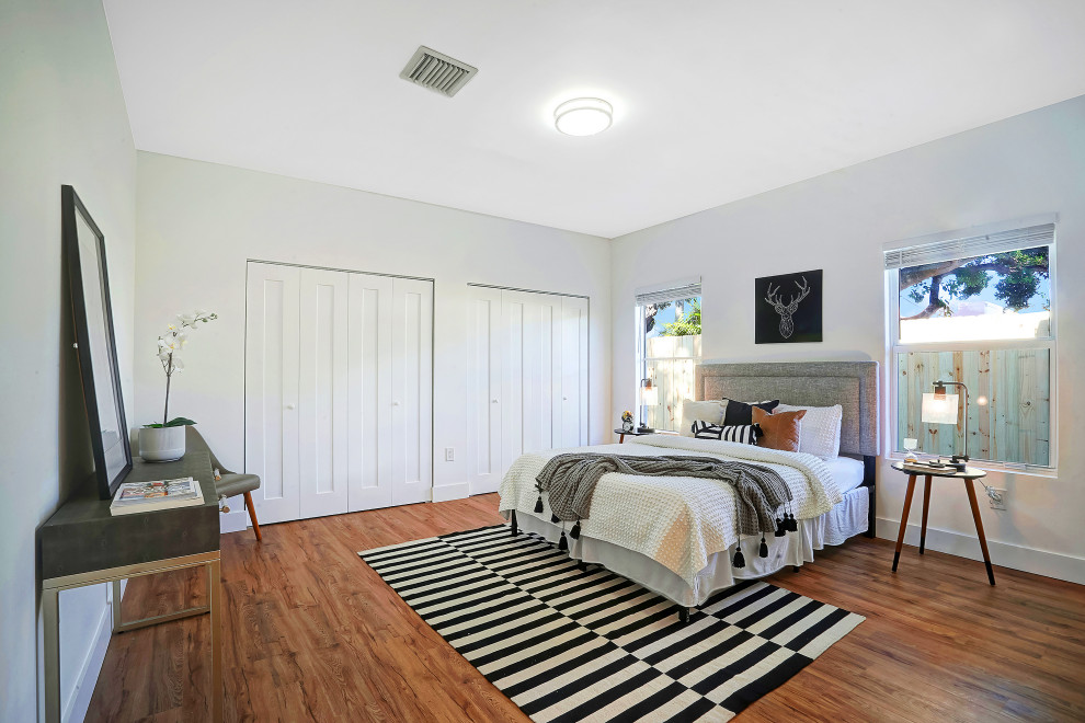 Diseño de dormitorio actual de tamaño medio sin chimenea con paredes blancas, suelo de madera clara y suelo marrón