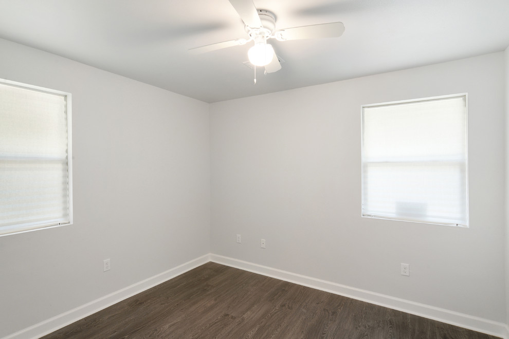 Imagen de habitación de invitados actual pequeña con paredes grises y suelo laminado
