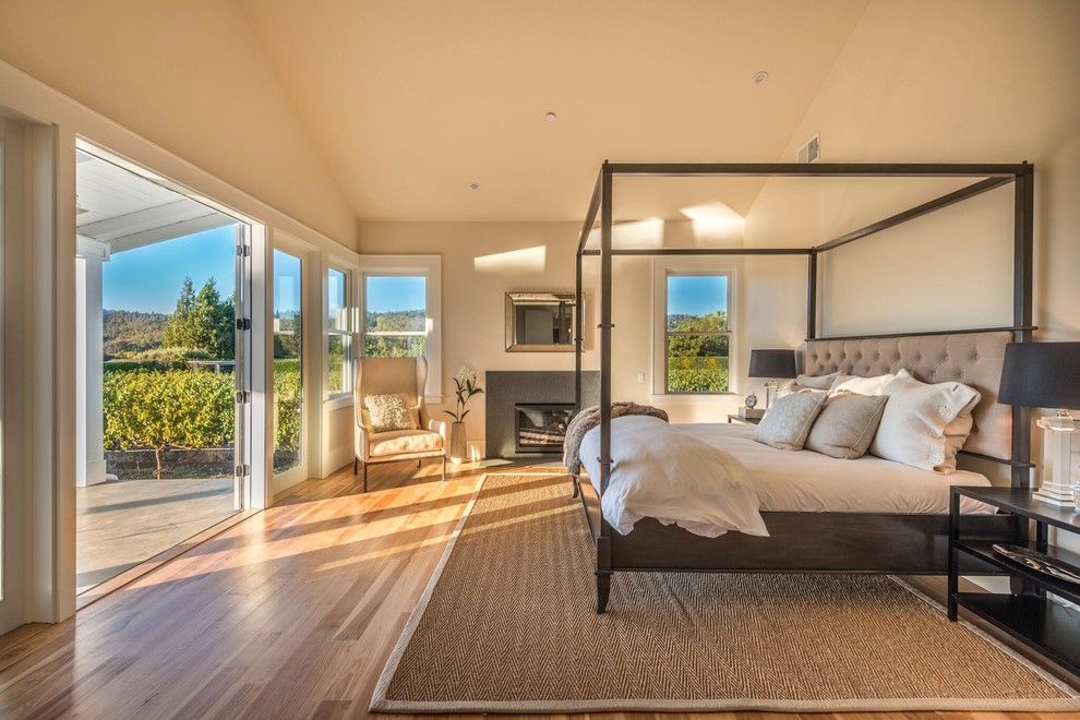 Idee per una camera da letto country con pareti beige, pavimento in legno massello medio, camino classico e pavimento marrone