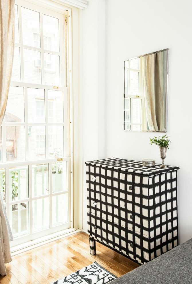 Kleines Stilmix Hauptschlafzimmer ohne Kamin mit weißer Wandfarbe und braunem Holzboden in New York
