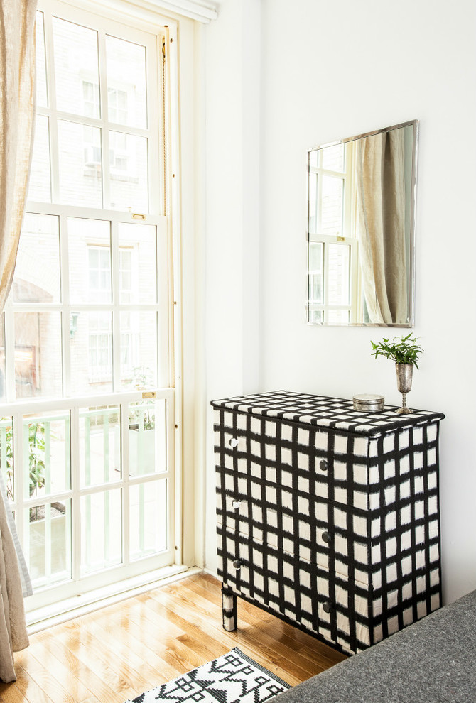 Small eclectic master medium tone wood floor bedroom photo in New York with white walls and no fireplace
