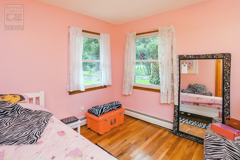 ニューヨークにある中くらいなエクレクティックスタイルのおしゃれな客用寝室 (ピンクの壁、無垢フローリング、茶色い床)