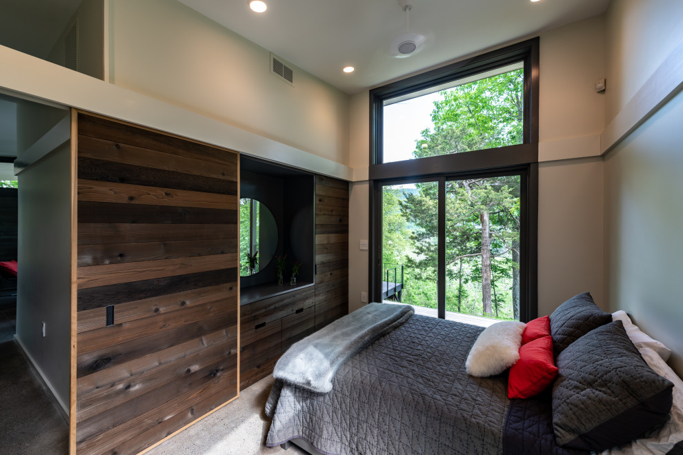 Cette image montre une petite chambre parentale minimaliste avec sol en béton ciré, un manteau de cheminée en béton et un sol gris.
