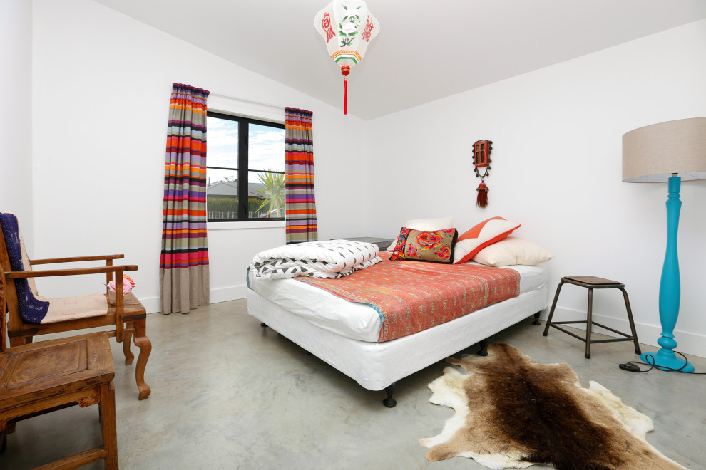 Eklektisk inredning av ett sovrum, med vita väggar, betonggolv och grått golv