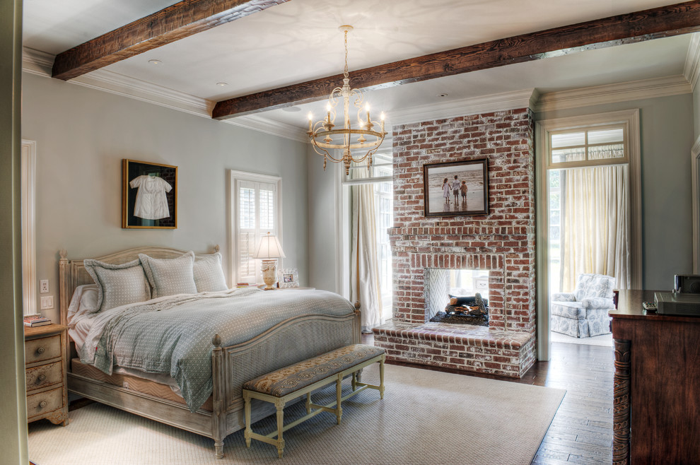 Inspiration for a mid-sized timeless master medium tone wood floor bedroom remodel in Other with gray walls, a brick fireplace and a two-sided fireplace