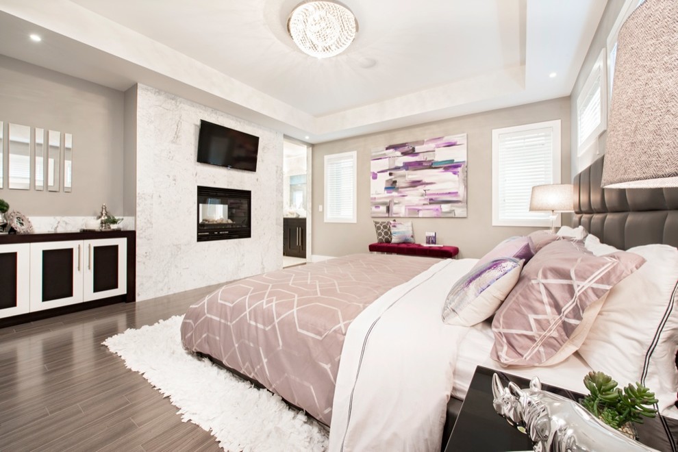 Photo of a large traditional master bedroom in Calgary with beige walls, medium hardwood flooring, a ribbon fireplace and a tiled fireplace surround.