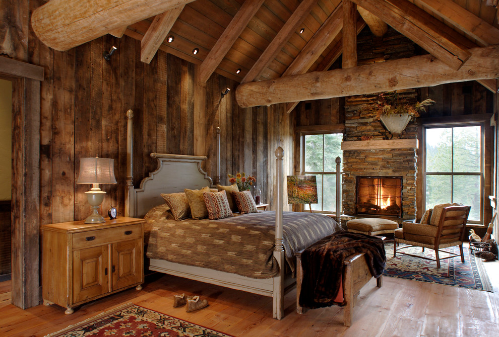 Large rustic master bedroom in Sacramento with beige walls, light hardwood flooring, a standard fireplace, a stone fireplace surround, beige floors and feature lighting.