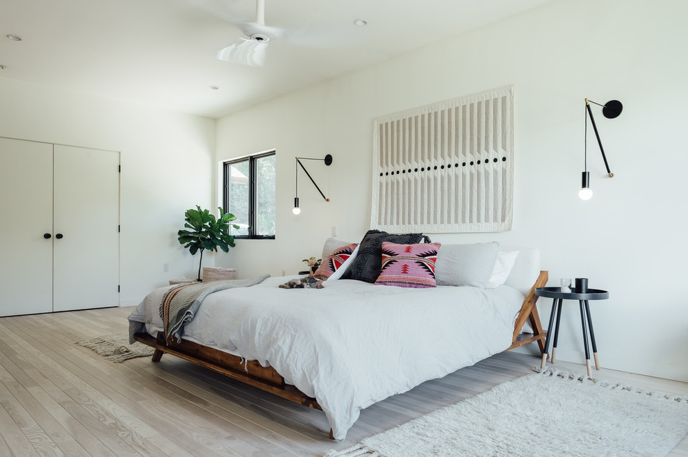 Imagen de dormitorio principal ecléctico de tamaño medio con paredes blancas y suelo de madera clara