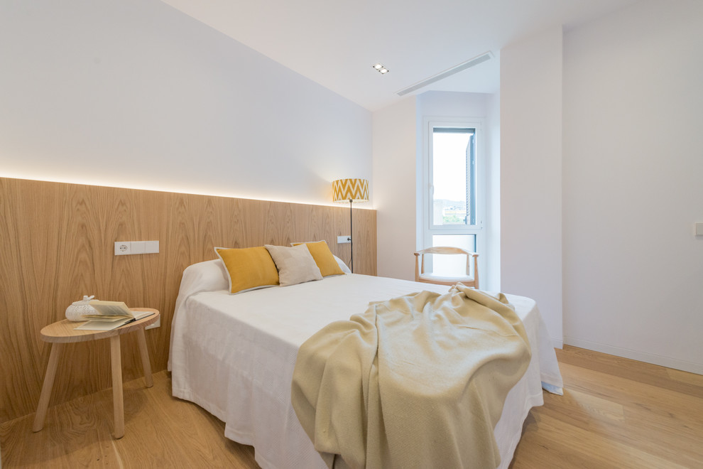 Imagen de dormitorio nórdico de tamaño medio sin chimenea con paredes blancas y suelo de madera clara