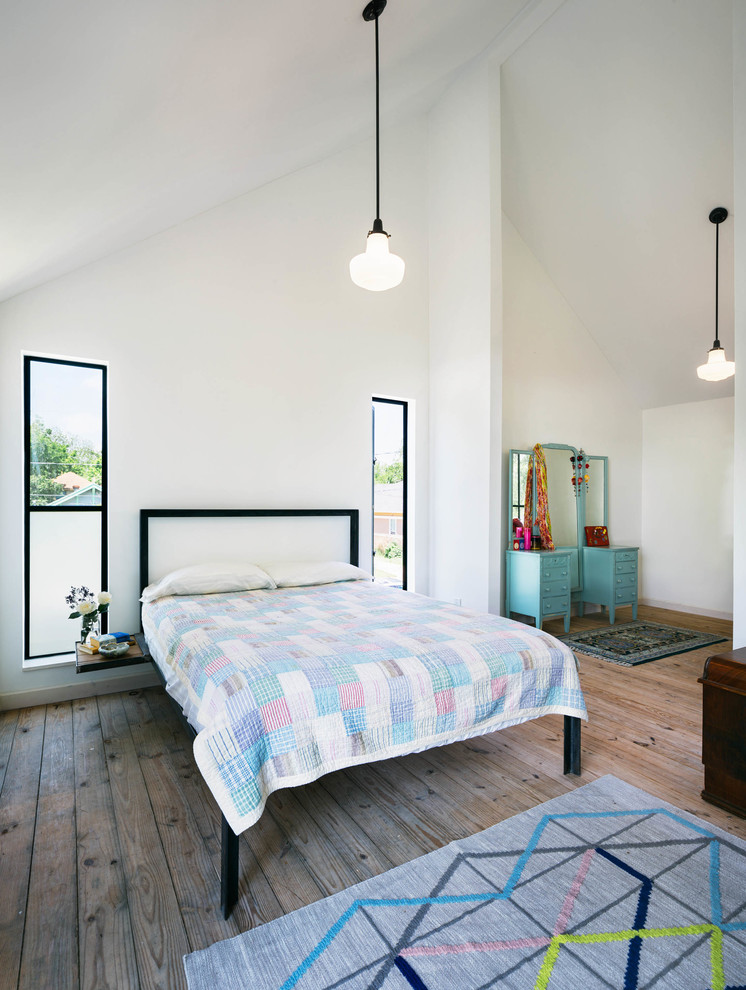 Foto de dormitorio industrial con paredes blancas y suelo de madera en tonos medios