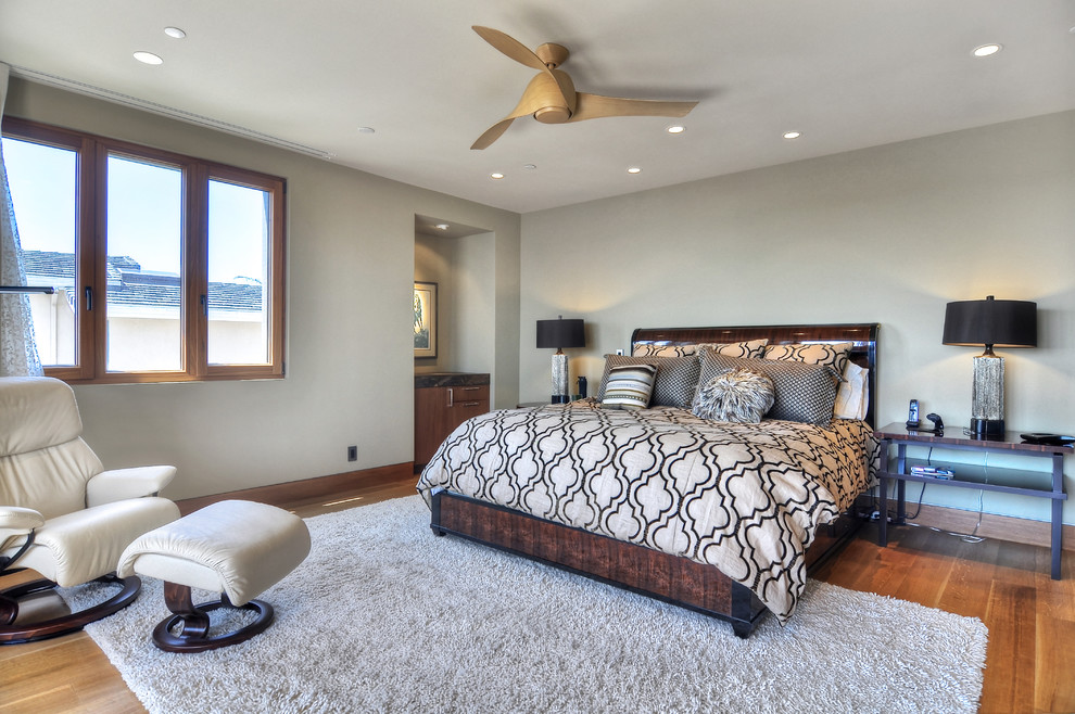 Immagine di una camera da letto design con pareti grigie e pavimento in legno massello medio