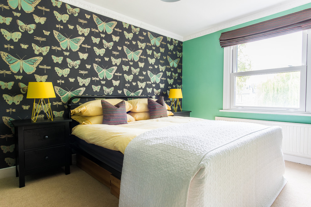 Medium sized contemporary bedroom in London with green walls, carpet and beige floors.