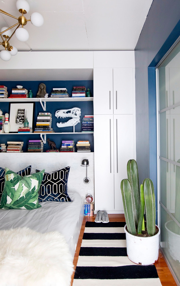 Ispirazione per una piccola camera da letto stile loft boho chic con pareti blu, parquet chiaro e pavimento marrone