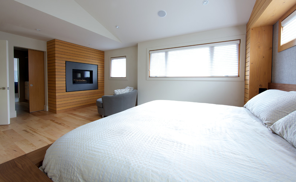 Свежая идея для дизайна: большая хозяйская спальня в современном стиле с белыми стенами, светлым паркетным полом, стандартным камином и фасадом камина из дерева - отличное фото интерьера