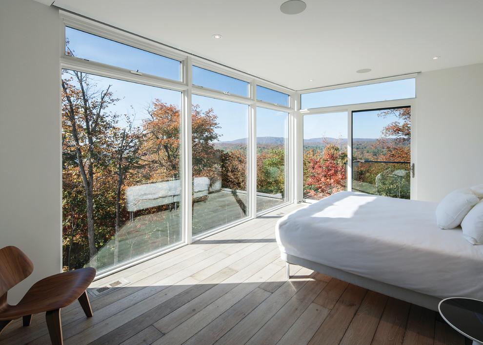 Großes Modernes Hauptschlafzimmer ohne Kamin mit weißer Wandfarbe und braunem Holzboden in Montreal