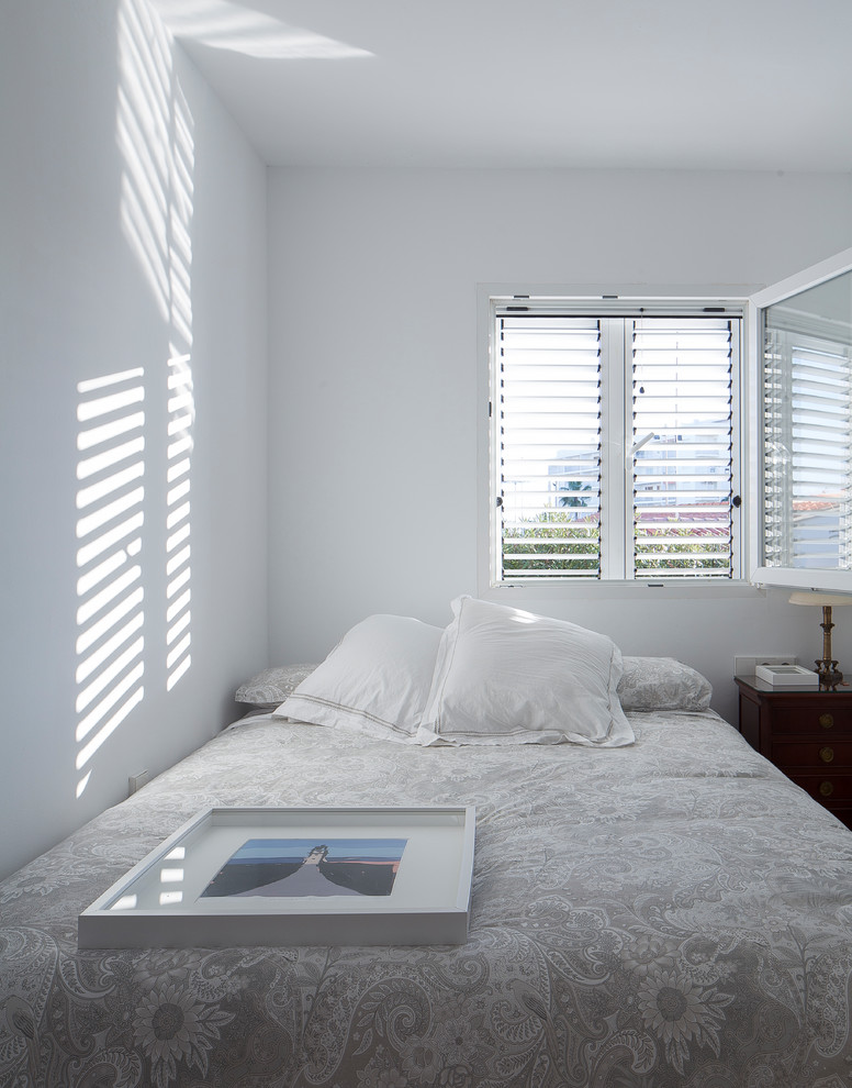 Modelo de habitación de invitados mediterránea de tamaño medio con paredes blancas y suelo de madera clara