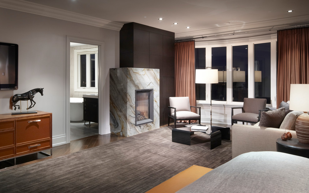 Diseño de dormitorio principal clásico renovado grande con paredes grises, suelo de madera oscura y marco de chimenea de piedra