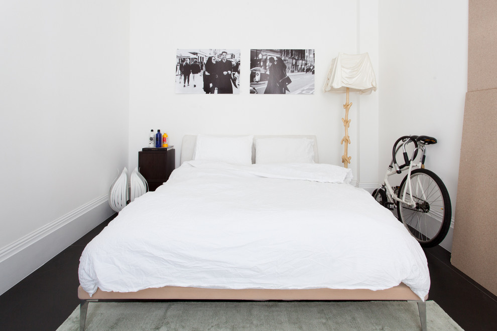 Modelo de habitación de invitados minimalista de tamaño medio sin chimenea con paredes blancas, suelo de cemento y suelo negro