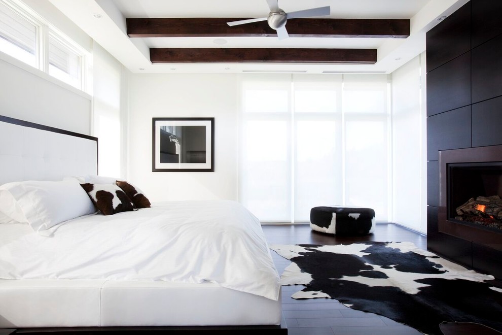 Großes Modernes Hauptschlafzimmer mit weißer Wandfarbe, dunklem Holzboden, Kamin, Kaminumrandung aus Holz und braunem Boden in Toronto