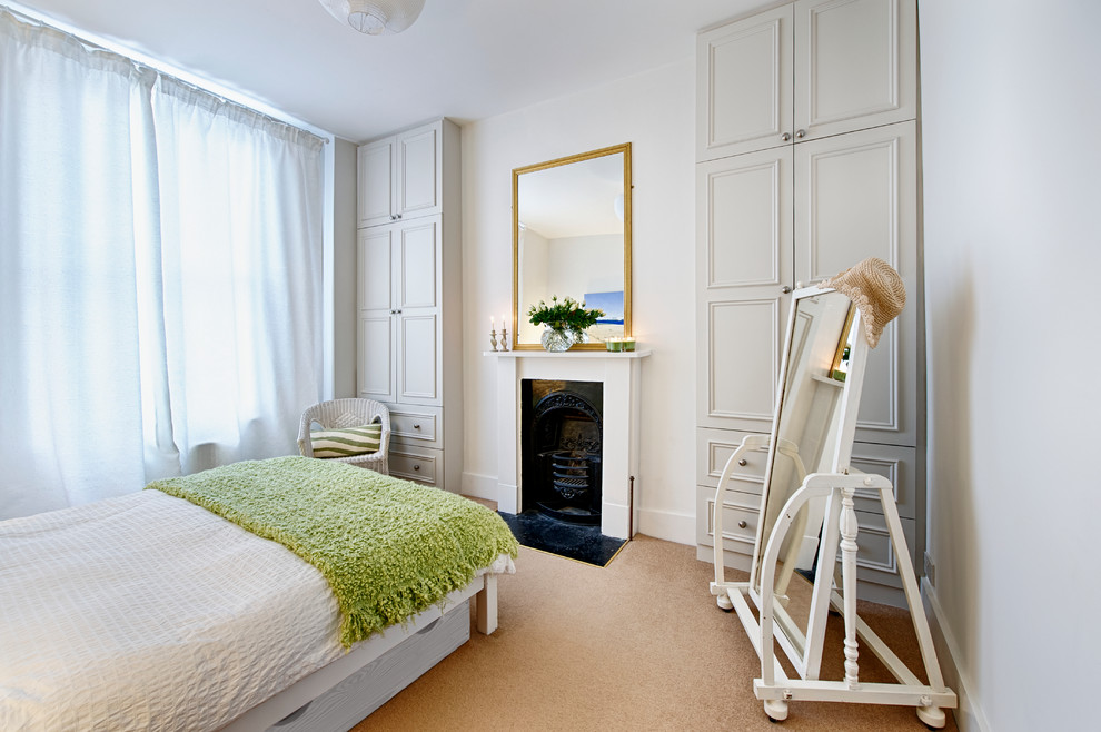 ロンドンにある中くらいなトラディショナルスタイルのおしゃれな客用寝室 (白い壁、カーペット敷き、標準型暖炉、木材の暖炉まわり)