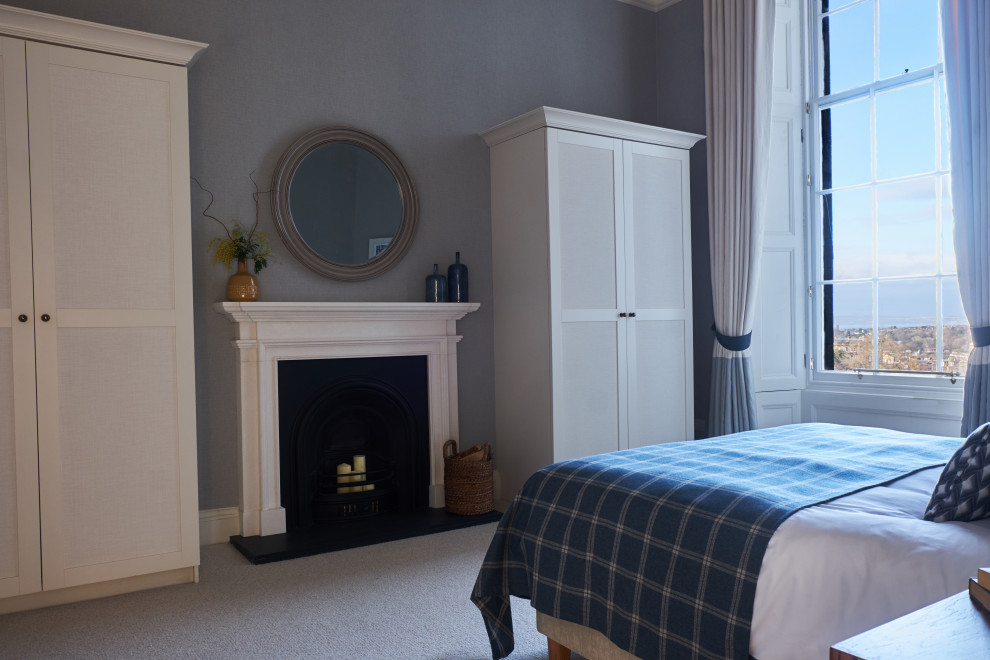 Свежая идея для дизайна: большая хозяйская спальня в стиле неоклассика (современная классика) с синими стенами, ковровым покрытием, стандартным камином, фасадом камина из камня и белым полом - отличное фото интерьера