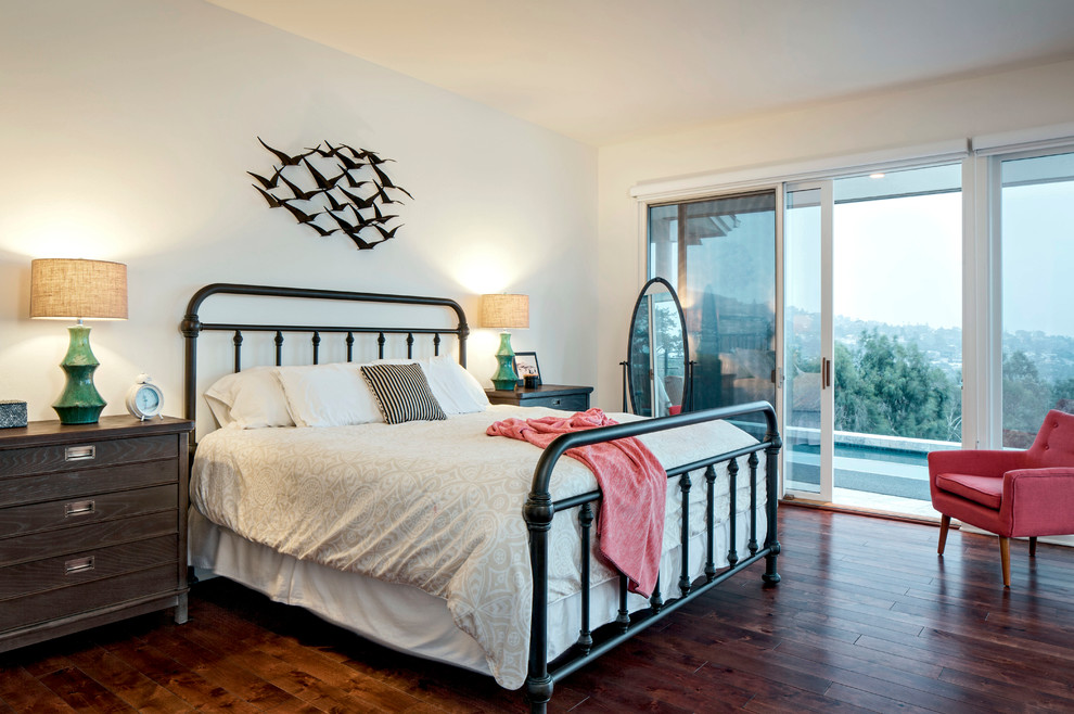 Ejemplo de dormitorio principal costero grande sin chimenea con paredes blancas y suelo de madera oscura