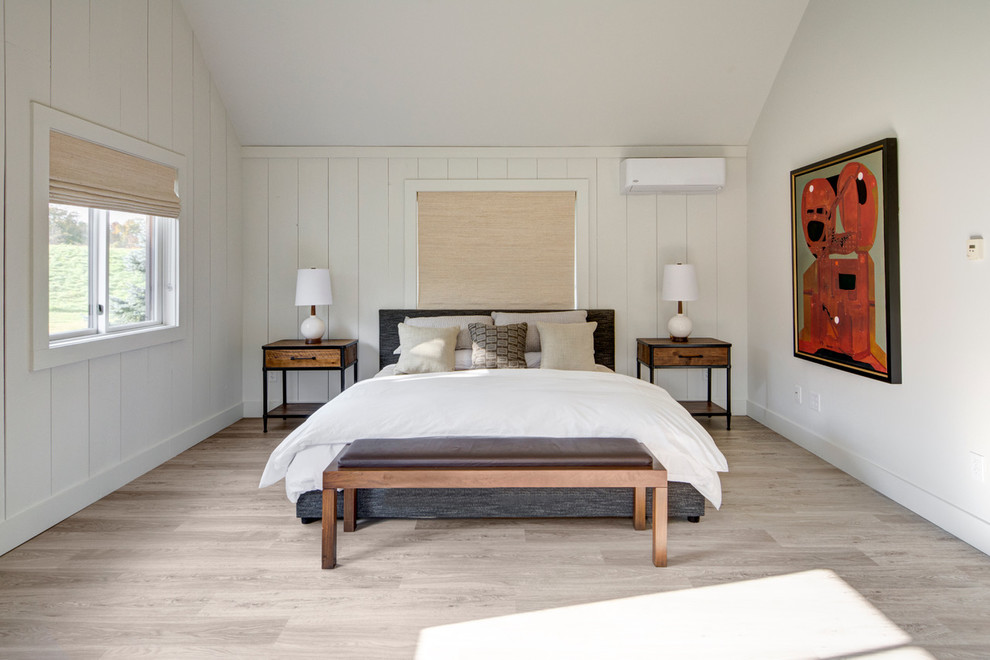 Ejemplo de habitación de invitados de estilo de casa de campo con paredes blancas y suelo de madera clara